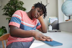 Is Your Child Using Too Much Social Media? Teenage boy putting down phone and looking depressed